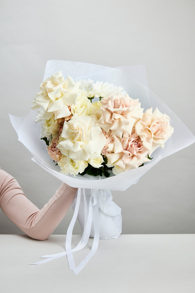 Daydream Bouquet of soft white and pink flowers wrapped in white paper created by flowerdose.