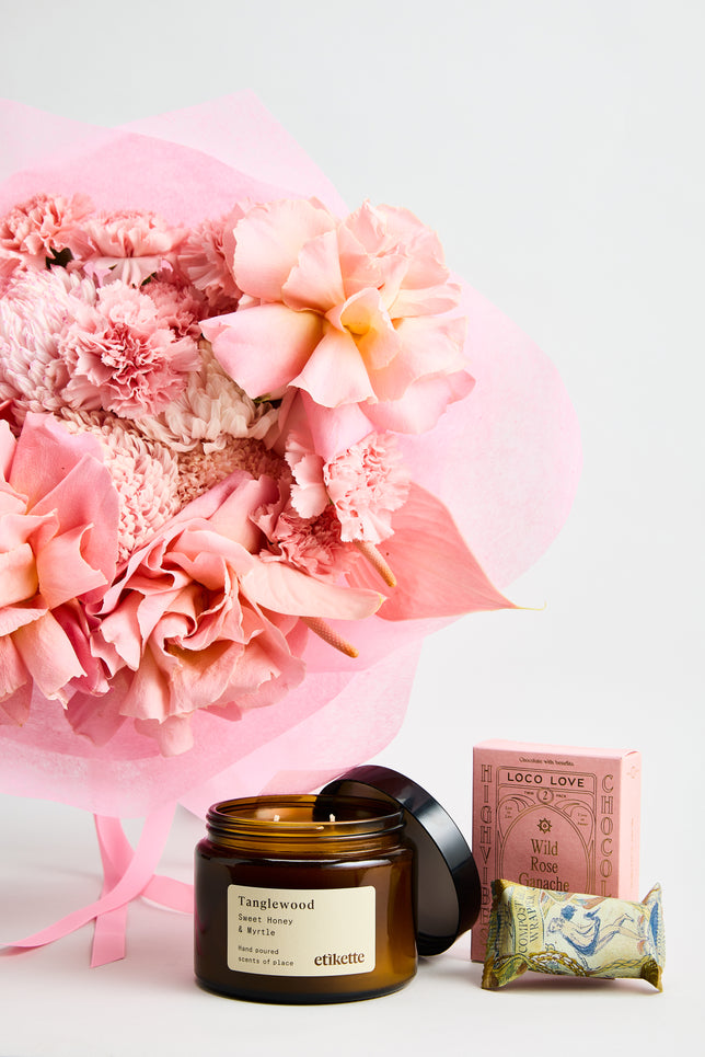 Pink Affair Gift Set is a elegant pink flower bouquet featuring premium roses, anthuriums, carnations, and chrysanthemums, wrapped in soft pink paper with satin ribbons, paired with a Tanglewood Sweet Honey & Myrtle candle and Loco Love Wild Rose Ganache chocolate — created by luxury Melbourne florist  flowerdose, the perfect gift for birthdays, anniversaries, and romantic occasions.